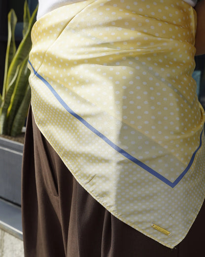 Pañuelo cuadrado amarillo con lunares blancos y borde azul.